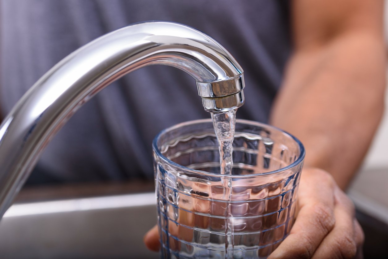 hand-with-drinking-glass-filling-water-from-kitchen-faucet