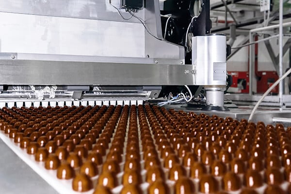 Rows of chocolates on a conveyer in a chocolate factory